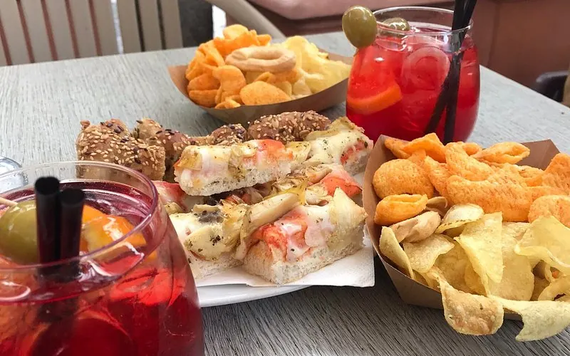 Tavolino all'aperto del Caffè Roberta con due spritz, focacce e patatine