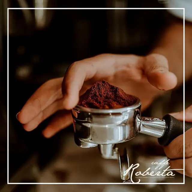 Portafiltro con caffè macinato fresco tra le mani del barista del Caffè Roberta